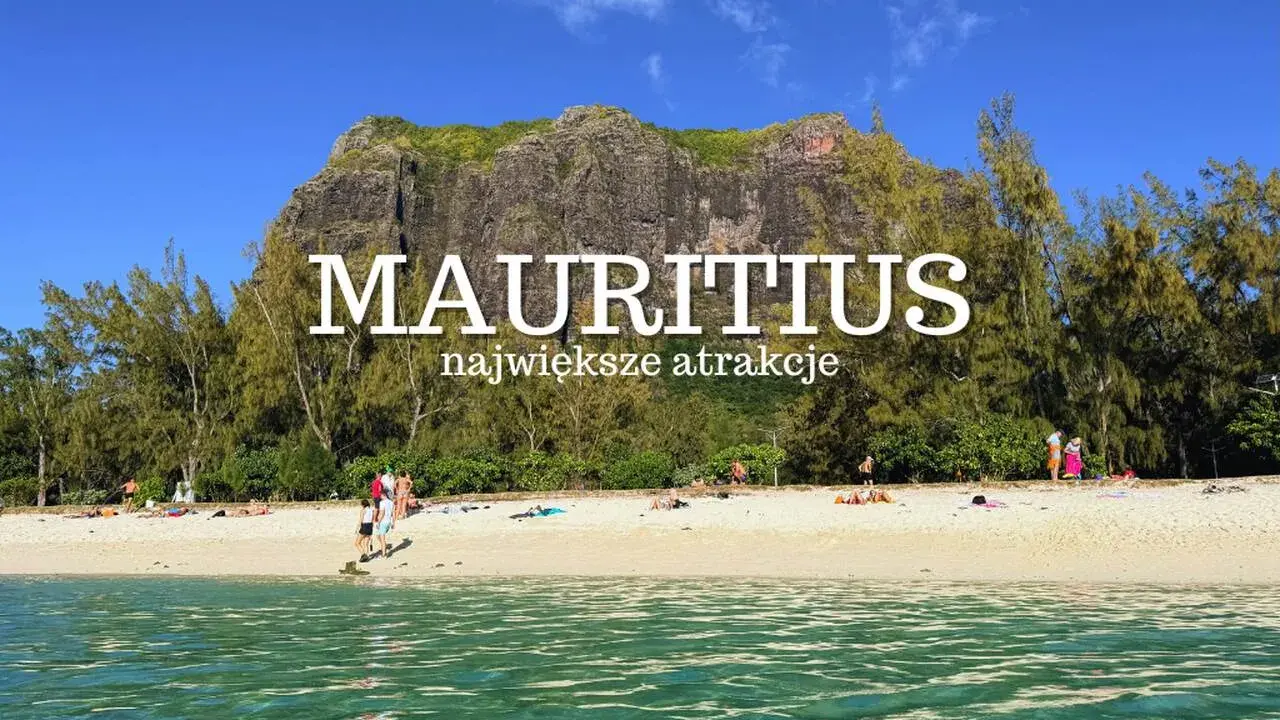 Plaża na Mauritiusie z turkusową wodą, piaszczystym brzegiem i skalistym masywem w tle.