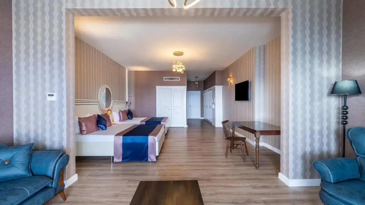 Przytulny pokój w Orange County Resort Alanya z dwoma łóżkami, niebieską sofą i stołem.