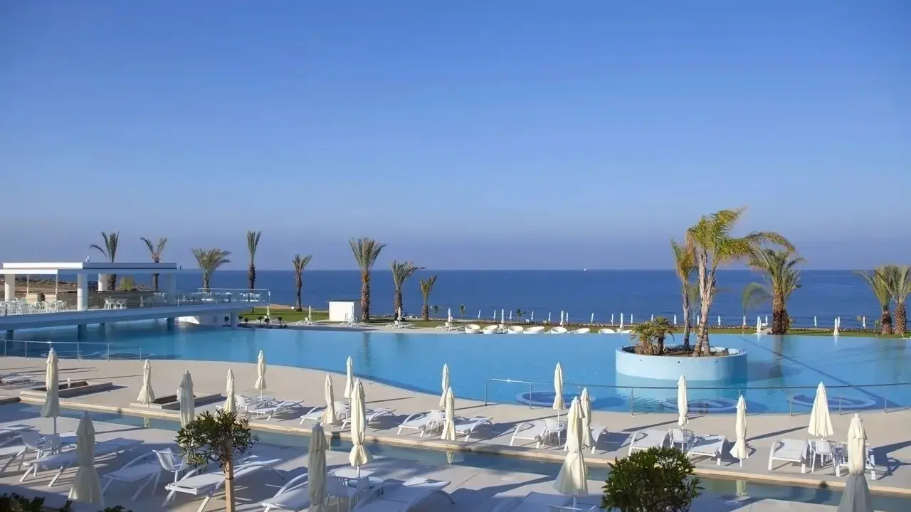 Luksusowy basen z palmami i widokiem na morze. Wiele opinii o King Evelthon Beach Hotel and Resort potwierdza jego piękno.