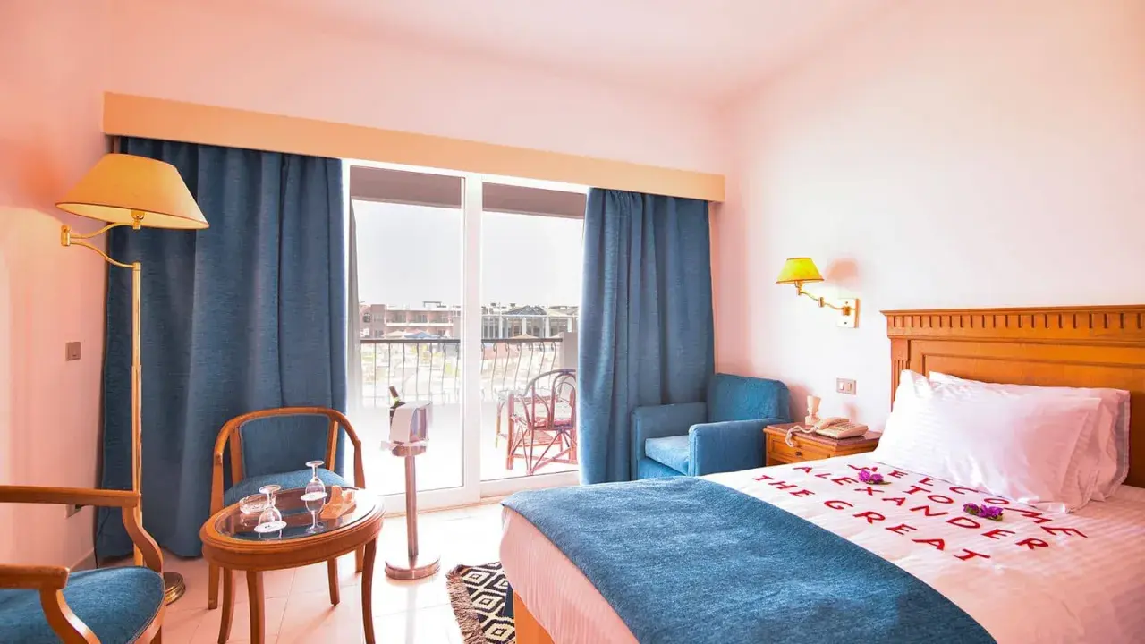 Pokój hotelowy z napisem "Welcome to Alexander the Great" na pościeli. Opinie o tym miejscu mogą być pozytywne.