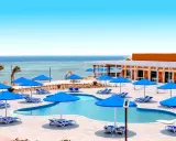 Basen z niebieskimi parasolami i leżakami, widok na morze. Idealne miejsce na wakacje, jak w Pickalbatros Portofino Marsa Alam.