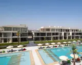 Nowoczesne budynki hotelowe Rixos z basenami i leżakami pod palmami.