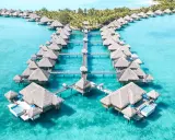 Domy na wodzie z krytymi strzechą dachami w turkusowej wodzie, Polinezja Francuska.