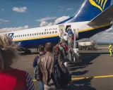 Pasażerowie wsiadają do samolotu Ryanair. Zastanawiasz się, ile kosztuje odprawa na lotnisku? Tutaj nie ma dodatkowych opłat.