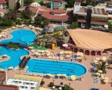 Widok z lotu ptaka na kompleks basenów i budynków hotelowych. Wiele osób odpoczywa na leżakach pod parasolami. Gypsophila holiday village opinie są pozytywne.