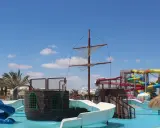 Djerba Aqua Resort (ex. Sun Connect) z pirackim statkiem i kolorowymi zjeżdżalniami wodnymi pod błękitnym niebem.