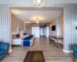 Przytulny pokój w Orange County Resort Alanya z dwoma łóżkami, niebieską sofą i stołem.