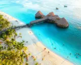 Rajska plaża na Zanzibarze z palmami i restauracją na wodzie. Sprawdź aktualne zanzibar ceny, by zaplanować wymarzone wakacje.