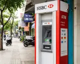 Bankomat HSBC w Hanoi, gotowy do wypłaty waluty. W tle widać ruchliwą ulicę z motocyklami i sklepami.