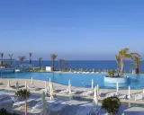 Luksusowy basen z palmami i widokiem na morze. Wiele opinii o King Evelthon Beach Hotel and Resort potwierdza jego piękno.