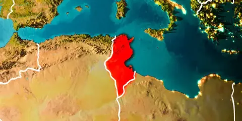 Mapa świata z zaznaczoną na czerwono Tunezją, otoczoną przez Morze Śródziemne i pustynię.
