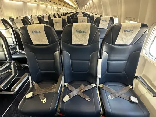 Puste, ciemne fotele w samolocie Enter Air z pasami bezpieczeństwa.