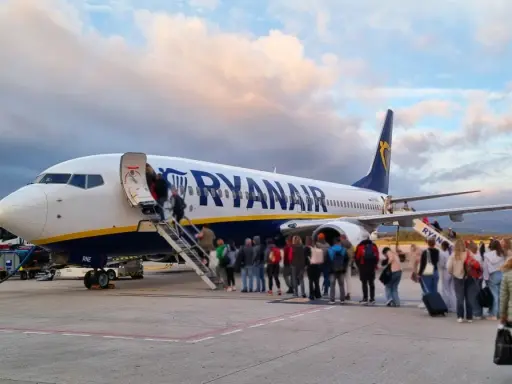 Samolot Ryanair z pasażerami wchodzącymi po schodach na pokład.