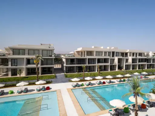 Nowoczesne budynki hotelowe Rixos z basenami i leżakami pod palmami.