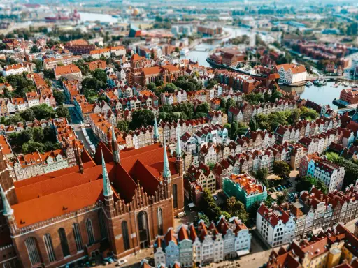 Widok z lotu ptaka na zabytkowe miasto z ceglaną katedrą i kolorowymi kamienicami.