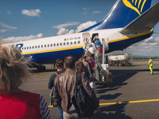 Pasażerowie wsiadają do samolotu Ryanair. Zastanawiasz się, ile kosztuje odprawa na lotnisku? Tutaj nie ma dodatkowych opłat.