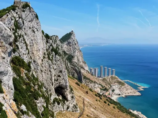 Widok na Skałę Gibraltarską z jaskinią, budynkami i morzem.