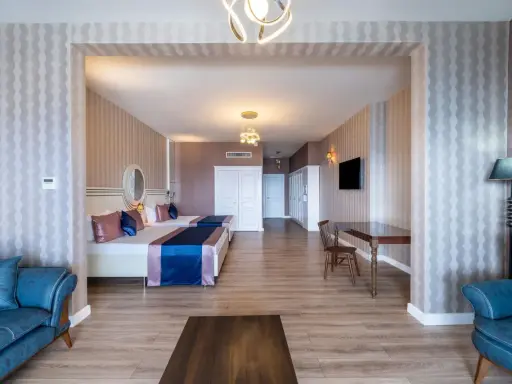 Przytulny pokój w Orange County Resort Alanya z dwoma łóżkami, niebieską sofą i stołem.