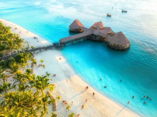 Rajska plaża na Zanzibarze z palmami i restauracją na wodzie. Sprawdź aktualne zanzibar ceny, by zaplanować wymarzone wakacje.