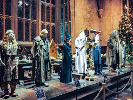 Manekiny postaci z Harry'ego Pottera w strojach, w tym Hagrid i Dumbledore, obok choinki.