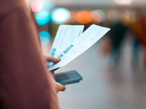 Dłoń trzymająca kilka biletów lotniczych i paszport.