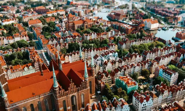Widok z lotu ptaka na zabytkowe miasto z ceglaną katedrą i kolorowymi kamienicami.