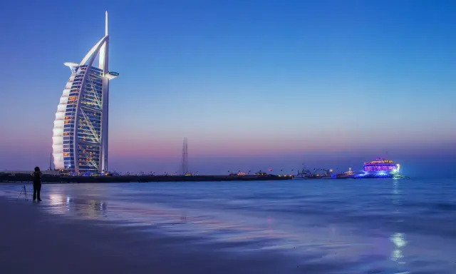Wieżowiec Burdż al-Arab i plaża w Dubaju o zmierzchu.
