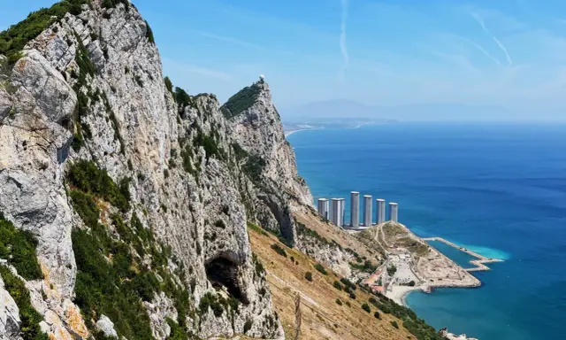 Widok na Skałę Gibraltarską z jaskinią, budynkami i morzem.