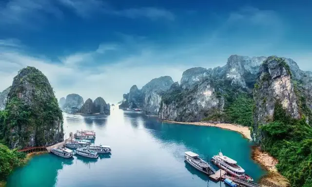 Widok na zatokę Ha Long w Wietnamie z łodziami i skalistymi wyspami.