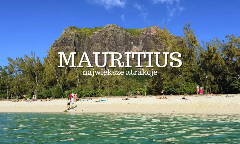 Plaża na Mauritiusie z turkusową wodą, piaszczystym brzegiem i skalistym masywem w tle.