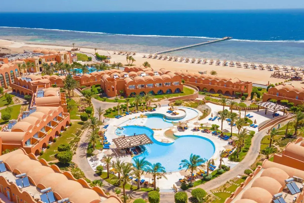 Widok z lotu ptaka na kompleks hotelowy Novotel Marsa Alam z basenami, palmami i plażą. Idealne miejsce na wakacje, zgodnie z wieloma pozytywnymi novotel marsa alam opinie.