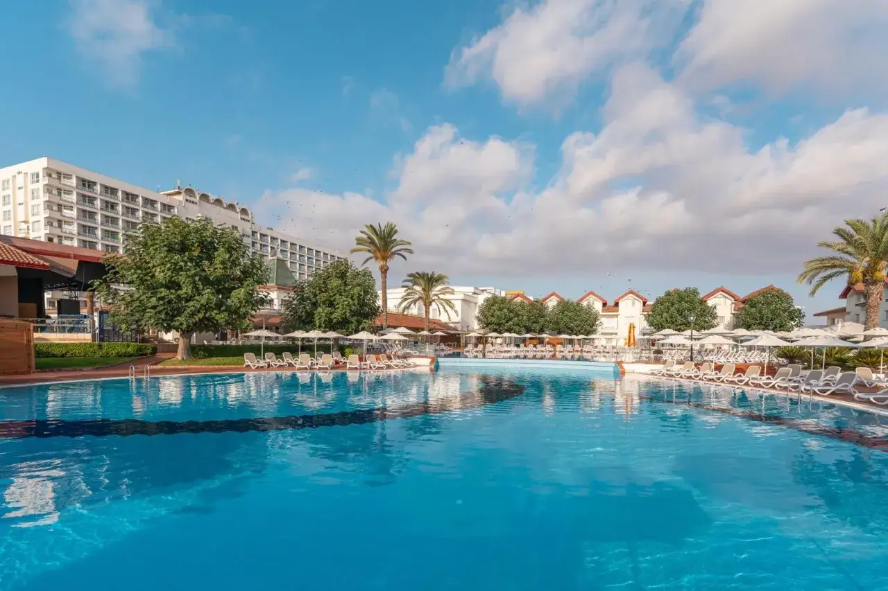 Basen hotelowy z leżakami i parasolami, idealny na wakacje. Wiele pozytywnych salamis bay conti opinie potwierdza jego urok.