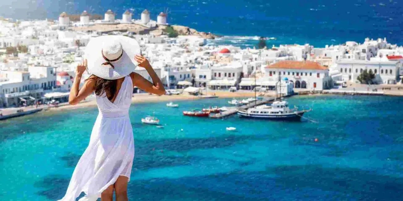 Kobieta w białej sukni podziwia widok na Mykonos. Sprawdź, jakie są grecja ceny, by zaplanować wymarzone wakacje!