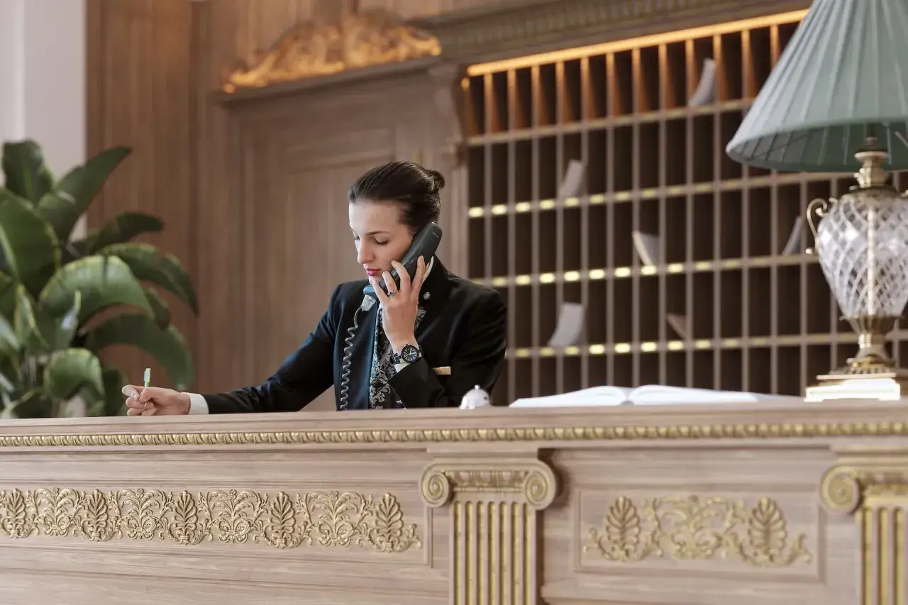 Recepcjonistka w eleganckim hotelu rozmawia przez telefon, notując coś na kartce. To idealne miejsce, by sprawdzić, co to za luksus.
